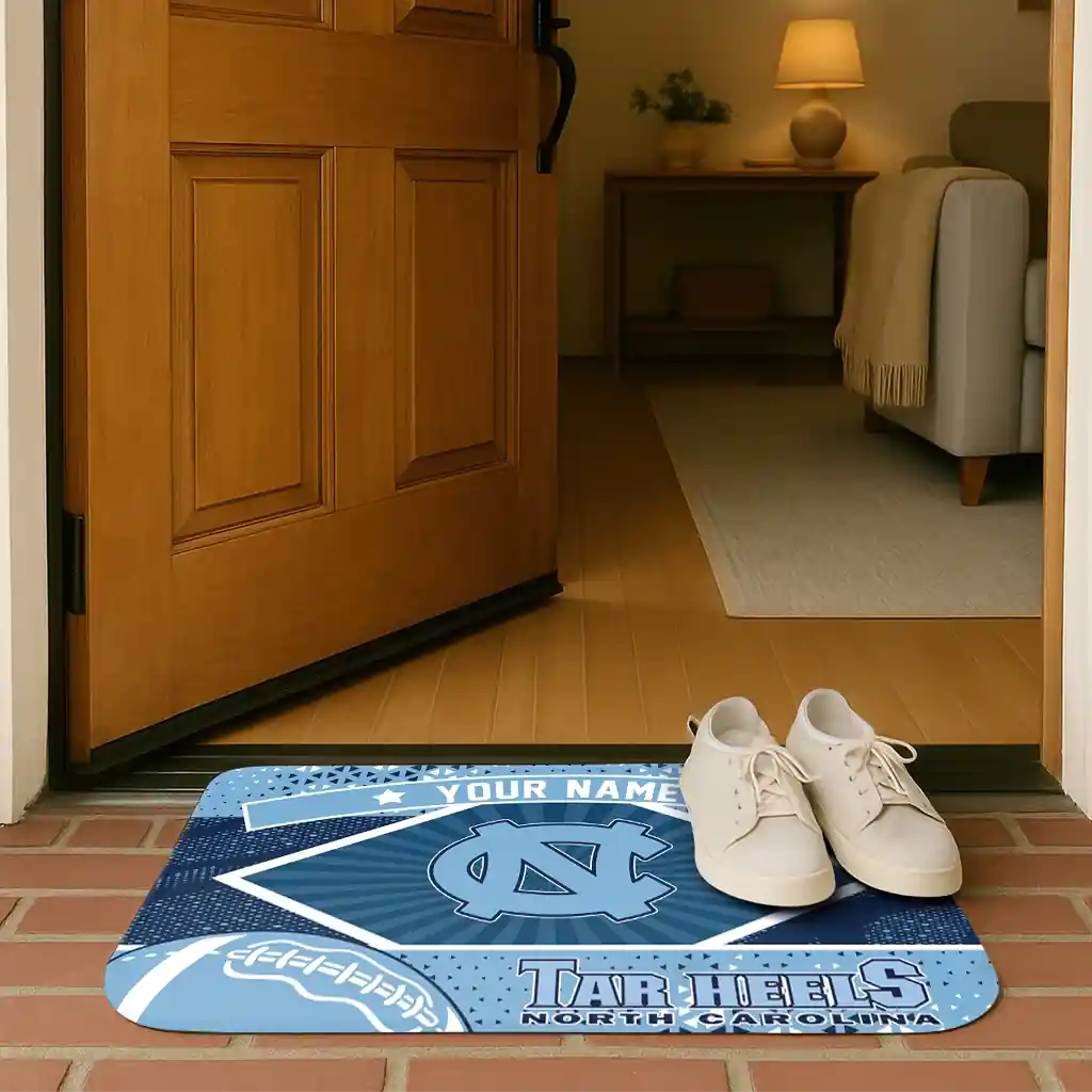 personalized-north-carolina-tar-heels-football-crest-light-blue-black-doormat-fashion-forward.webp